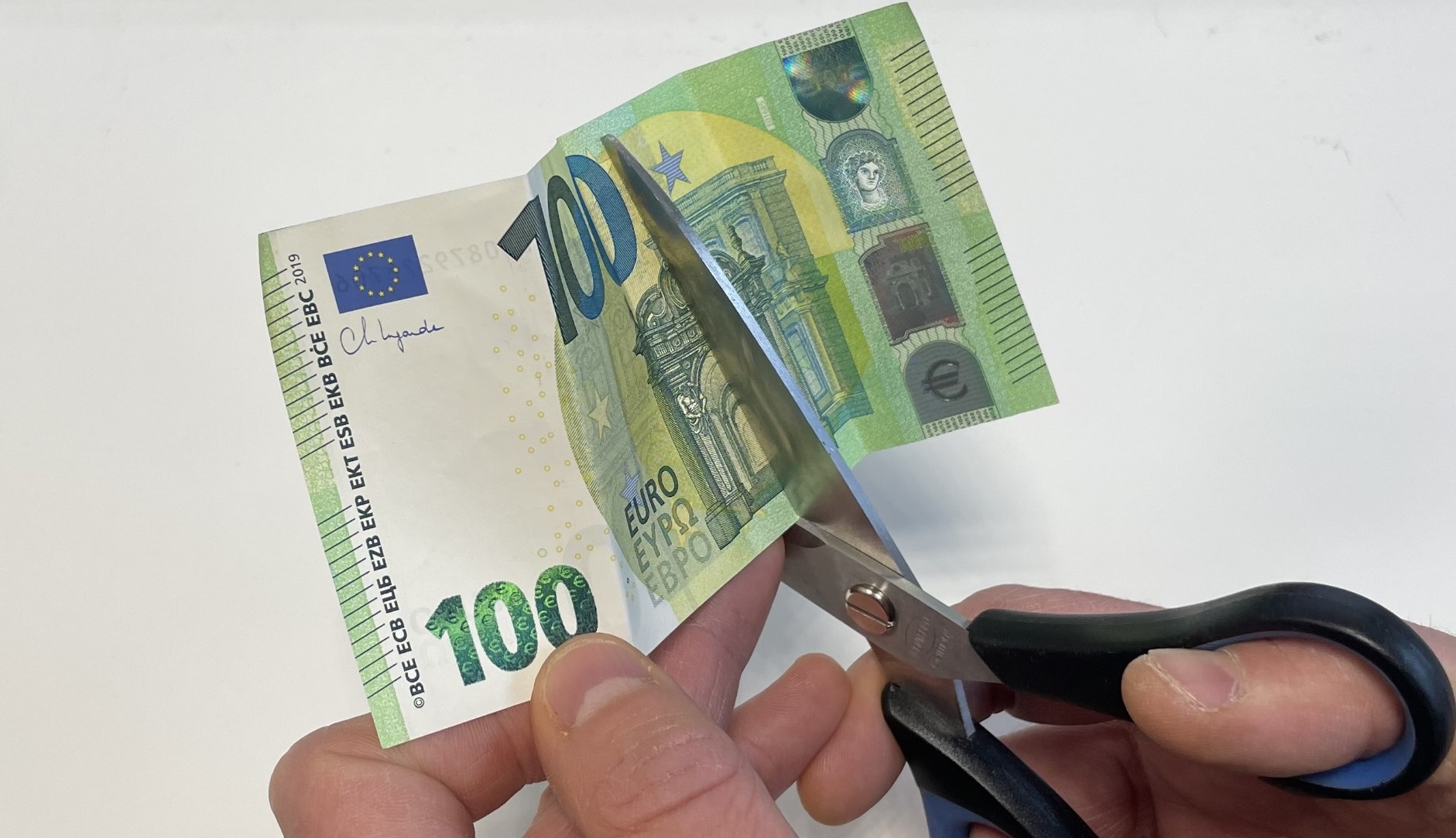 Euro-setelin leikkaaminen saksilla.